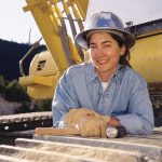 Close up of female worker standing in front of excavator